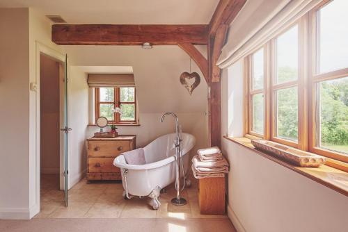 baño con bañera y ventana en Apple Tree Cottage, en Beckford