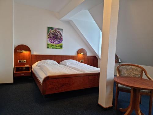 a bedroom with a bed and a chair and a table at Hotel Nassauer Hof in Limburg an der Lahn