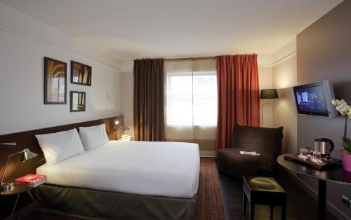 a hotel room with a white bed and a chair at Residence Mercure Paris La Defense Grande Arche in Nanterre
