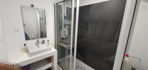 a bathroom with a glass shower and a sink at Apartamento T2-5m Aeroporto CR7 in Santa Cruz