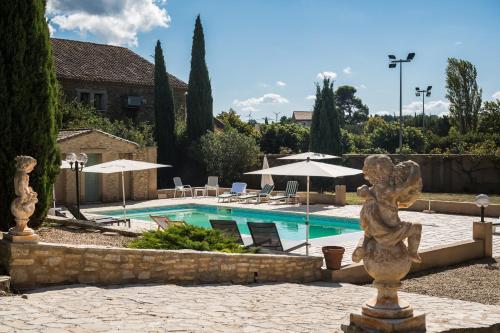 - une piscine avec une statue en face d'un bâtiment dans l'établissement Le gite de la closerie des iris, à Castelnau-dʼAude