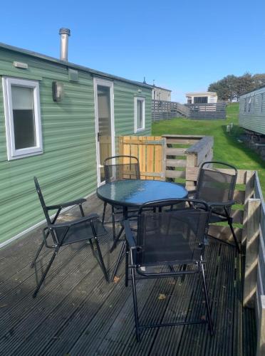 a patio with a table and chairs on a deck at Loch Heron View in Newton Stewart