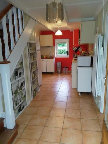 une cuisine avec des murs rouges et des placards blancs ainsi qu'un escalier. dans l'établissement Maison de famille entre terre et mer, à Lantic