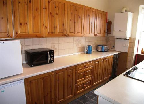 a kitchen with wooden cabinets and a black microwave at 26 Castle Street in Kirkcudbright