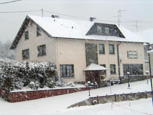 a building covered in snow with snow at Pension Hilberath in Kottenborn