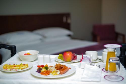a table with plates of food and fruit on it at Crowne Plaza - Dar Es Salaam by IHG in Dar es Salaam