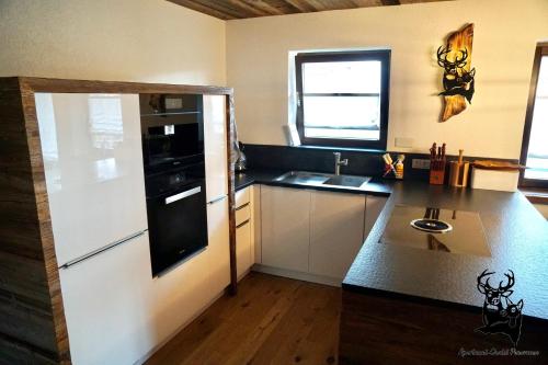 uma cozinha com um frigorífico preto e branco e um lavatório em Apartment-Chalet Panorama em Todtmoos