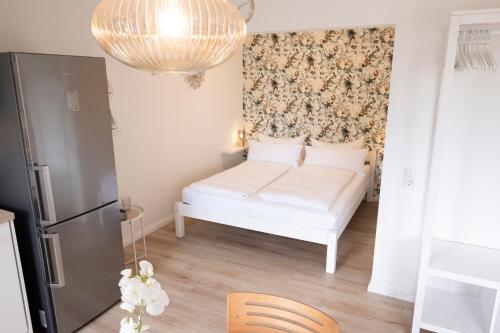 a small bedroom with a white bed and a chandelier at fewo1846 Strandresidenz Wassersleben - OstseeNest - modernes Studioapartment mit Balkon am Strand in Harrislee