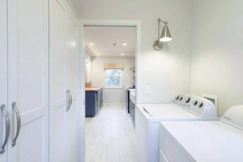 a white kitchen with a sink and a washing machine at Vine and View Cottage in Newberg