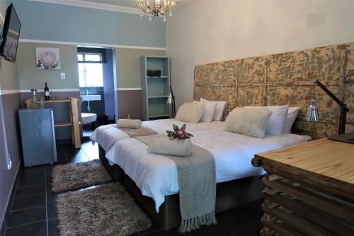 a bedroom with two beds with white sheets at Karoozin Village in Oudtshoorn