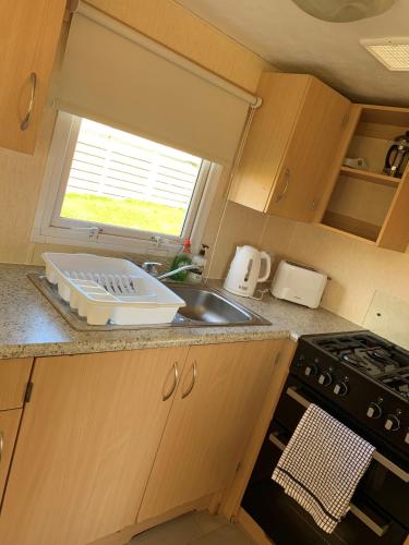 a kitchen with a sink and a stove and a window at Loch Heron View in Newton Stewart