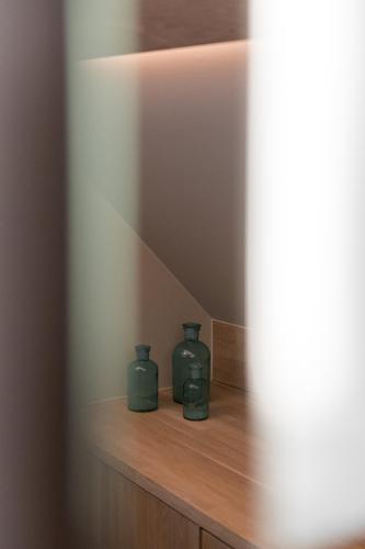 two green vases sitting on a wooden shelf at B&B Herenhuis in Izegem