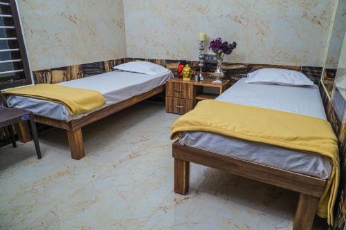 1 dormitorio con 2 camas y una mesa con flores en Royal Lodge, en Nāgercoil
