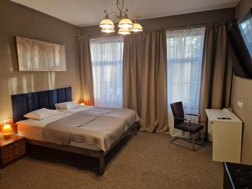 Schlafzimmer mit einem Bett, einem Stuhl und Fenstern in der Unterkunft Hotel Kārklu Muiža in Jelgava