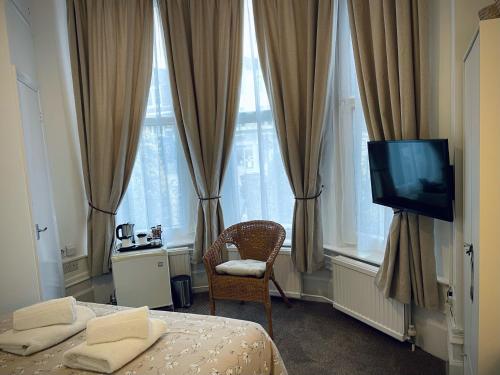 1 dormitorio con 2 camas, TV y ventanas en The Gateway Hotel en Londres