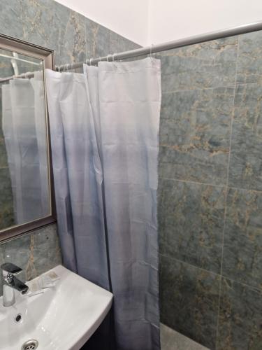 a bathroom with a shower curtain and a sink at Hotel Kārklu Muiža in Jelgava