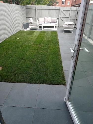 a patio with two white chairs and a lawn at 3 bedroom, 3 story town house in Liverpool