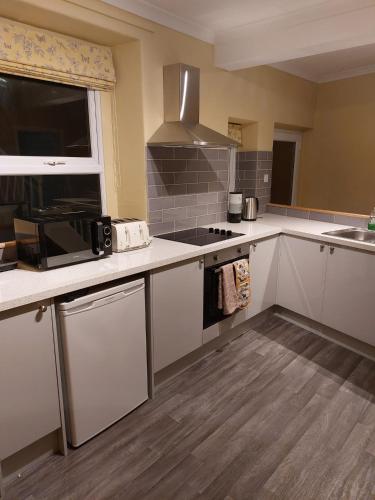 La cuisine est équipée de placards blancs et d'un four avec plaques de cuisson. dans l'établissement Entire two bedroom house in penrith, à Penrith