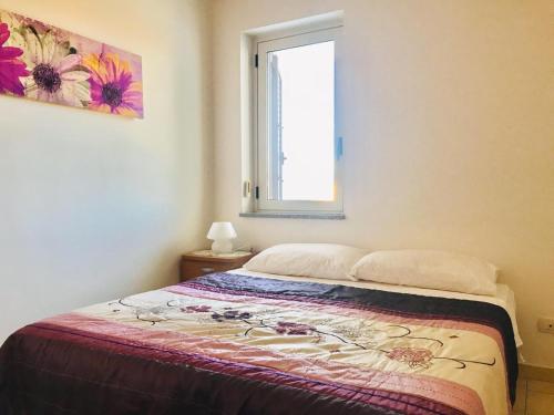 a bedroom with a bed with a window and a painting at San Rocco residence two bed apartments 5B2 5 in Isca sullo Ionio