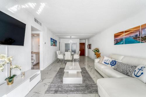 a living room with a white couch and a table at Extraordinary Oceanfront Condo - Heated Pool, Gym and Game Room - Hollywood Beach in Hollywood