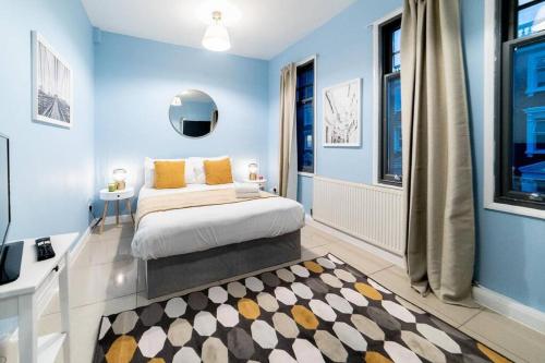 een slaapkamer met blauwe muren en een bed met gele kussens bij (Kensington Museum) 2 bedroom apartment London in Londen
