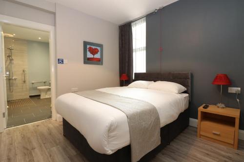 a bedroom with a large bed and a bathroom at The Muse - Luxury 5 Bedroom House in Belfast