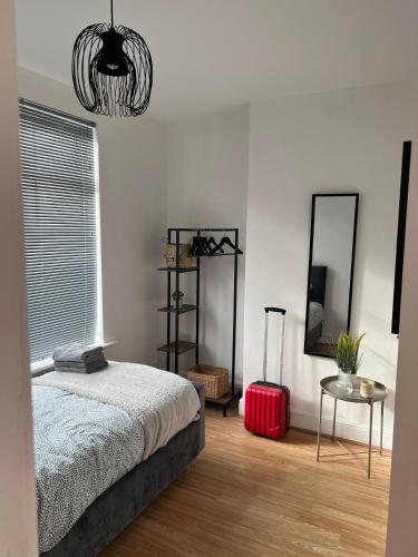 um quarto com uma cama, um espelho e uma mala vermelha em Cheerful 5 Bedrooms & En-Suite Bathrooms Town House em Northampton