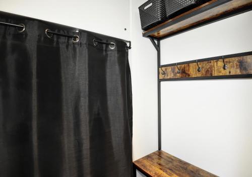 a black shower curtain next to a wooden shelf at Hameau 24#22 - Studio in Stoneham