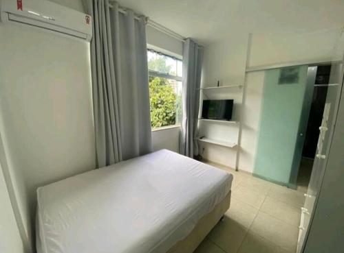 una camera con un letto bianco e una finestra di 1/4, sala, Farol da Barra. a Salvador