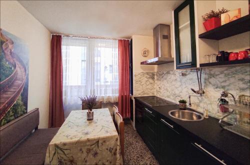 eine Küche mit einem Tisch, einem Waschbecken und einem Fenster in der Unterkunft Heart of the City in Banja Luka