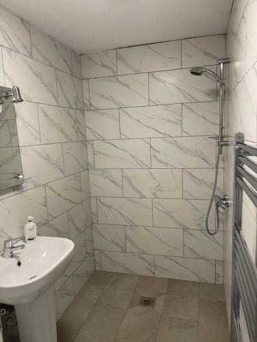 a white bathroom with a sink and a shower at Apple Barn Guest House in Wisbech