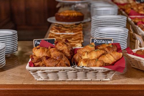 a table topped with baskets of pastries and plates at Casanova - Panoramic Rooms and Suites in San Quirico dʼOrcia