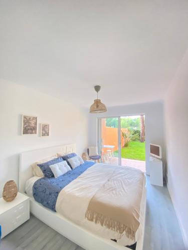 Un dormitorio blanco con una cama grande y una ventana en Charmoso apartamento na Herdade da Aroeira en Aroeira