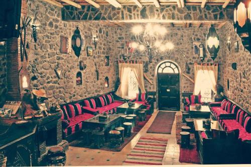 Habitación con sillas rojas y pared de piedra. en Riad imlil, en Imlil