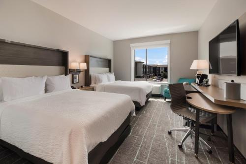 ein Hotelzimmer mit 2 Betten und einem Schreibtisch in der Unterkunft Holiday Inn & Suites - Mt Juliet Nashville Area, an IHG Hotel in Mount Juliet