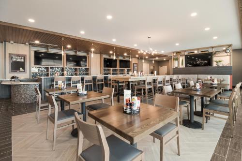 a restaurant with wooden tables and chairs and a bar at Holiday Inn & Suites - Mt Juliet Nashville Area by IHG in Mount Juliet