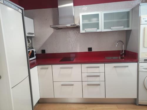 a kitchen with white cabinets and a red counter top at Precioso apartamento Centro de Sevilla in Seville