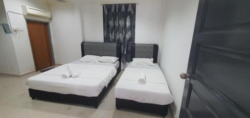 two beds in a small room with a door at RVH Kuala Terengganu in Kuala Terengganu