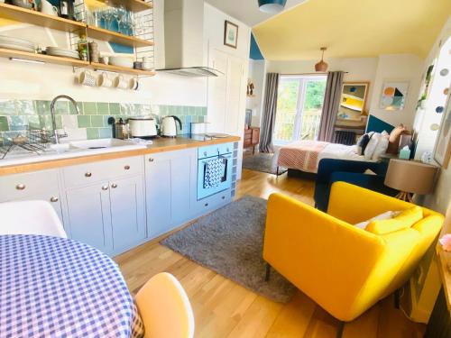 a kitchen with white cabinets and yellow chairs in a room at St Ives Balcony Flat in St Ives