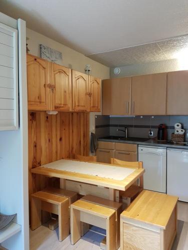 eine Küche mit Holzschränken, einem Tisch und Bänken in der Unterkunft Edelweiss Prapoutel les 7 Laux in Les Adrets