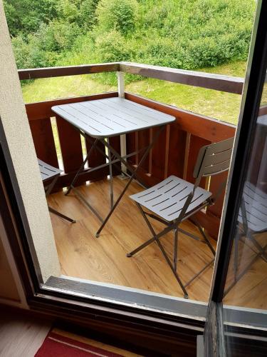 une table et deux chaises sur un balcon dans l'établissement Edelweiss Prapoutel les 7 Laux, à Les Adrets