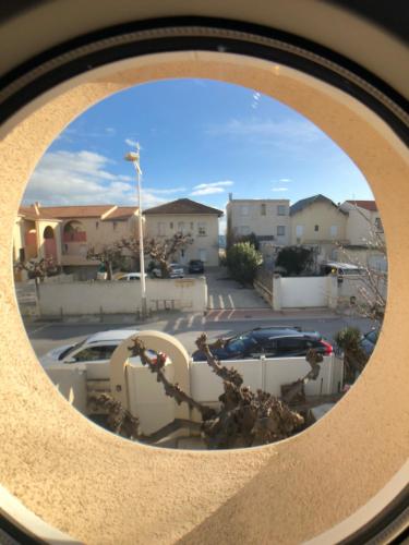 a round window with a view of a parking lot at Maison en bord de mer in Mauguio