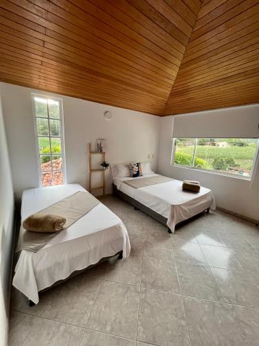 a bedroom with two beds and a wooden ceiling at Finca tres colinas in Lemos