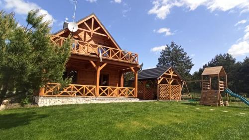 uma cabana de madeira com um parque infantil num quintal em Chata Sosenka em Sygontka