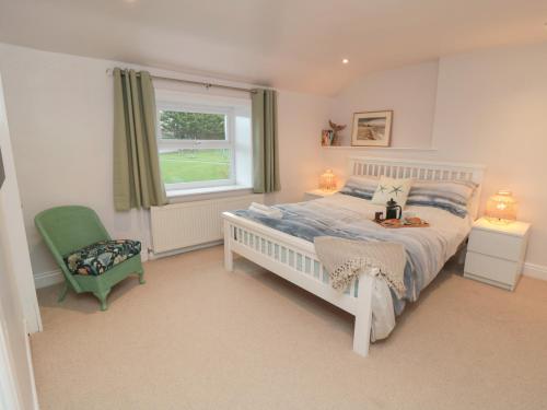 een slaapkamer met een bed, een stoel en een raam bij Salt Cottage in Redcar