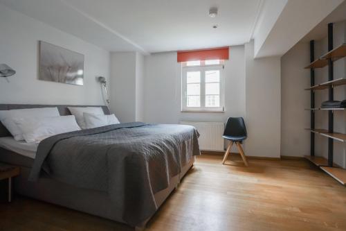 een slaapkamer met een bed, een raam en een stoel bij LOFT13 Traumhafte Wohnung mit Terrasse für 4 Gäste in Monschau