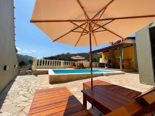 a patio with a bench and an umbrella and a pool at Loft Maika'i in Santo Antônio do Pinhal
