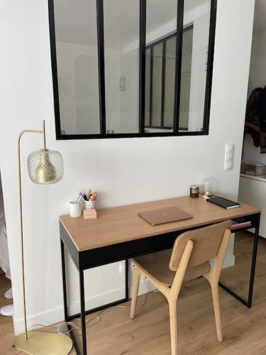 a desk with a chair and a mirror on a wall at Agréable et moderne studio à Neuilly avec jardin in Neuilly-sur-Seine
