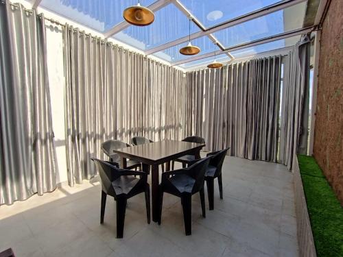 einen Tisch und Stühle auf einer Terrasse mit Fenstern in der Unterkunft Sapphire Mansion Vagamon in Vagamon