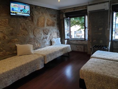 a room with two beds and a tv on the wall at PORTO RICO STUDIOS in Porto